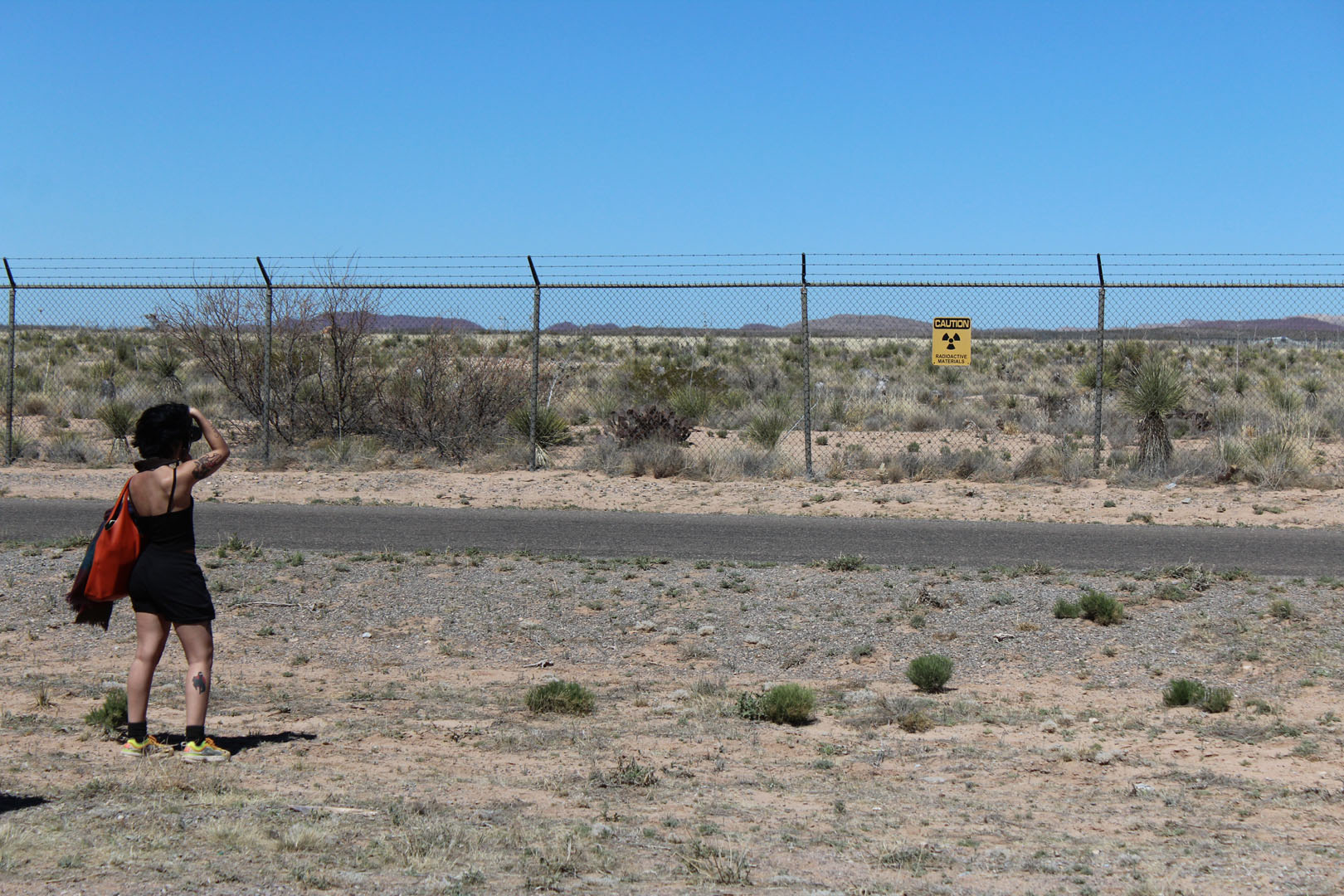Veronica Gibson '24 photographs a nuclear radiation warning on the fence that surrounds Trinity Site in March 2023. Photo submitted by Zeke Lloyd ’24.